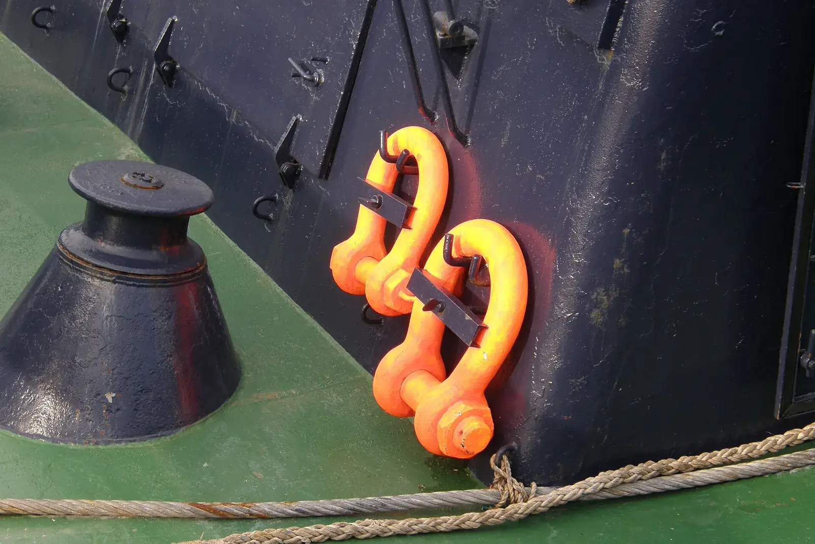 Orange shackles rigged to a mooring point on a ship