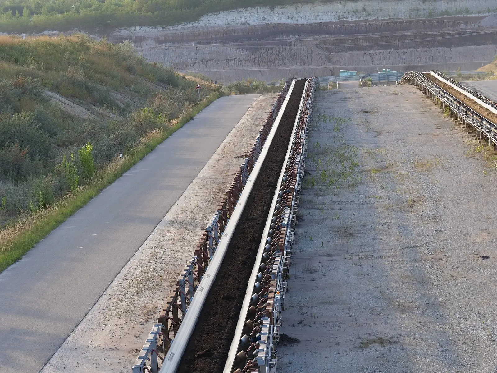 A long conveyor belt running through a surface mine